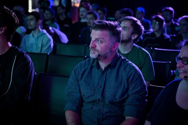 A shot of Matthew, another keynote speaker, in the front row watching Ben Holmes speak on stage.