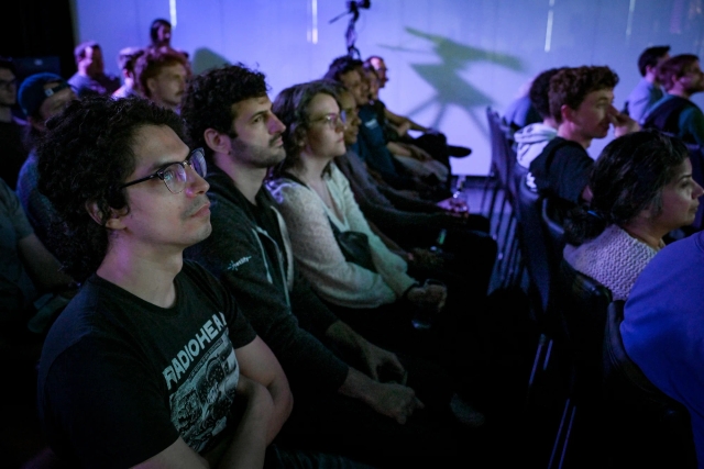 A shot of a row of audience members listening intently to the keynote presentation.