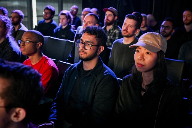 Audience members listening to Sarah Rainsberger speaking on stage.