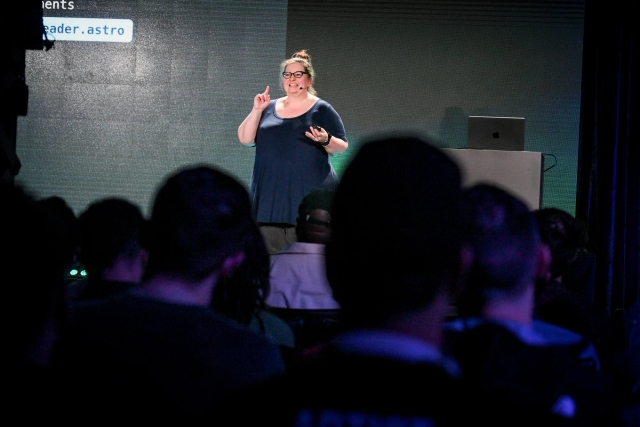 View from the audience of Sarah Rainsberger speaking on stage.