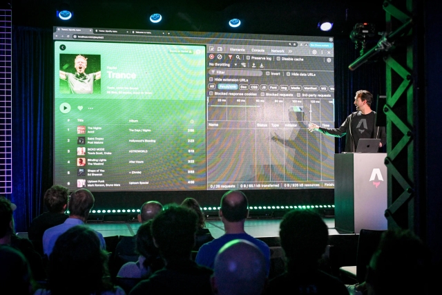 Fred K. Schott behind an Astro-branded podium as ahe does a live demo. On-screen is a code example for a Spotify clone. He has the developer network tool open.