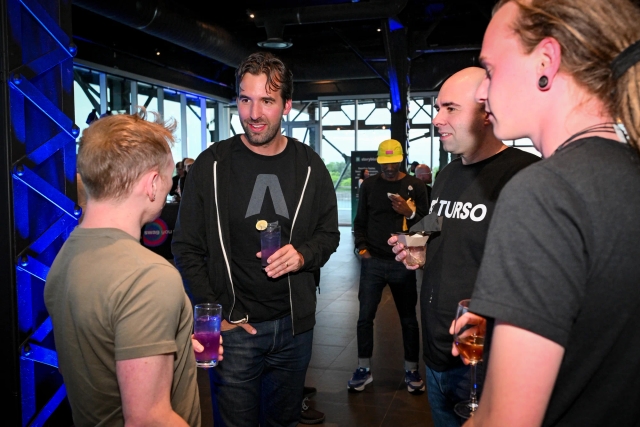 Fred K. Schott speaks to David Di Biase from Solid, Glauber from Turso, and Elian from Astro after the presentation. Everyone is holding a drink.