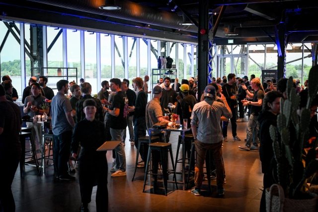 A shot of the crowd mingling along with servers serving food to guests.