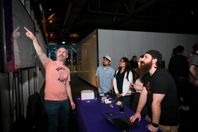 Sentry demos their product to a group of guest onlookers at their sponsor booth.